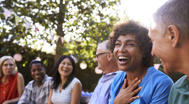 Group Of Mature Friends Socializing In Backyard Together